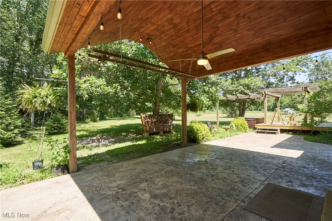 View of patio with ceiling fan and a pergola