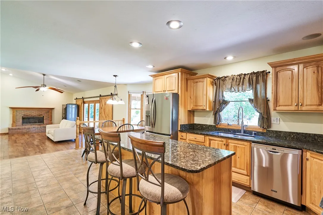 Kitchen with appliances with stainless steel finishes, a kitchen bar, open floor plan, recessed lighting, and dark stone counters