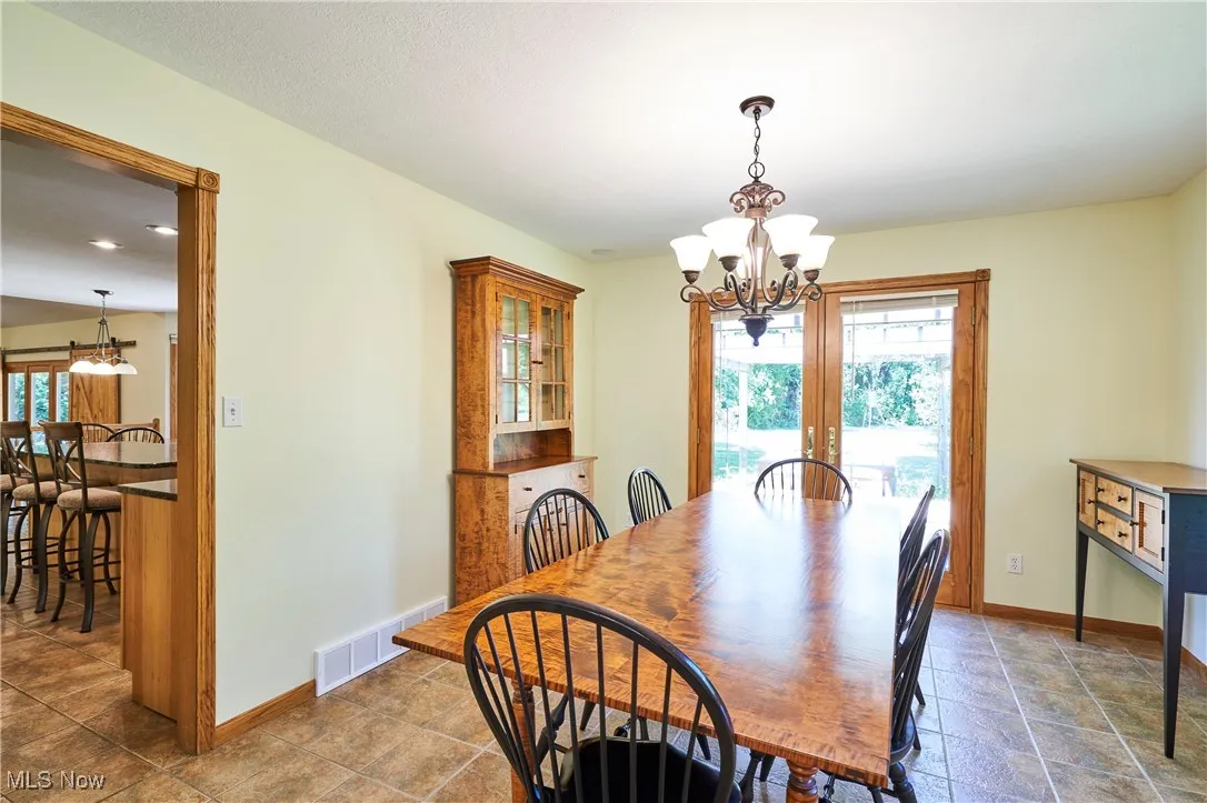 Dining space featuring a chandelier, french doors, and stone finish floors