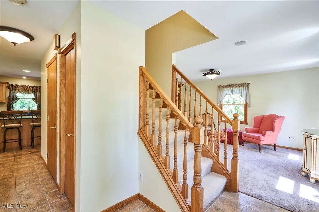 Stairs featuring plenty of natural light, recessed lighting, tile patterned flooring, and carpet