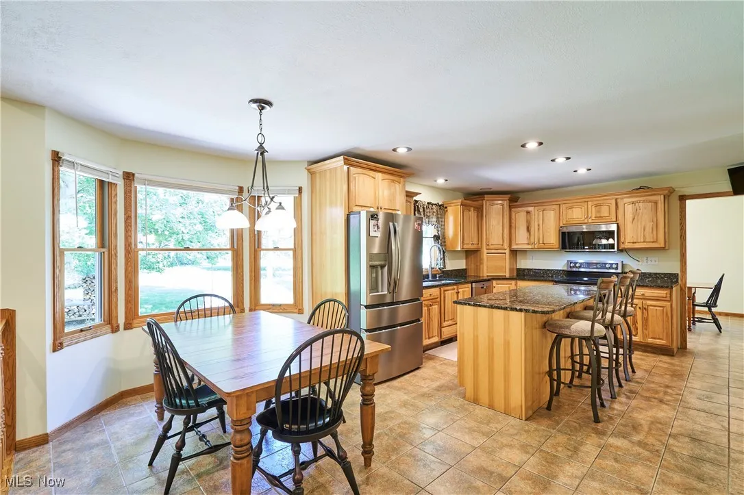 Kitchen with appliances with stainless steel finishes, a kitchen island, a breakfast bar, recessed lighting, and pendant lighting