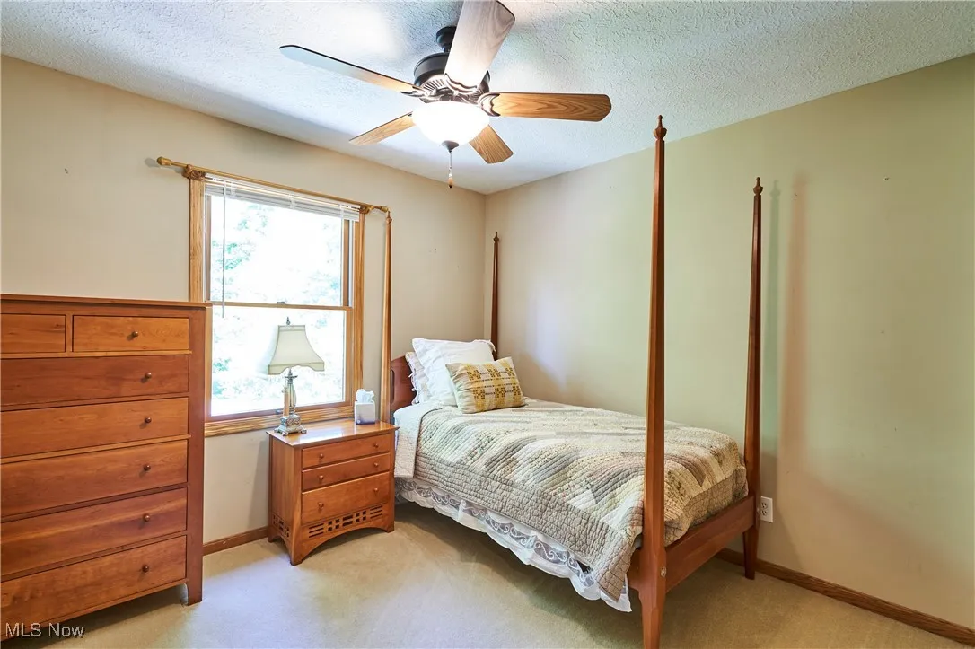 Bedroom featuring a textured ceiling, light colored carpet, and ceiling fan