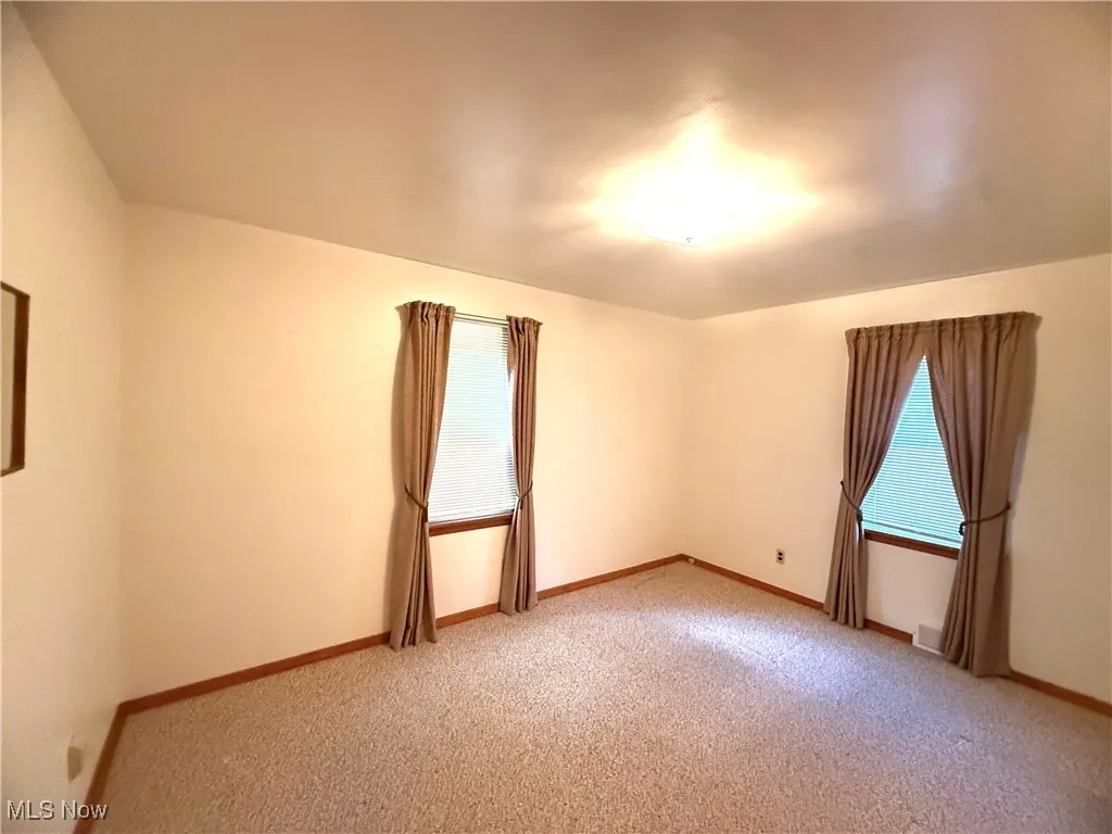Empty room featuring light carpet and healthy amount of natural light