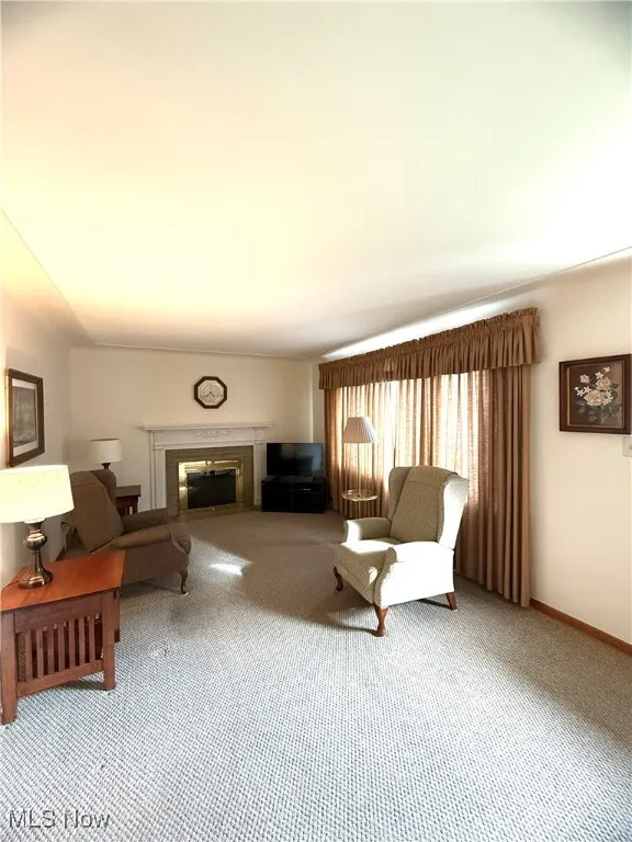 Carpeted living area featuring a glass covered fireplace
