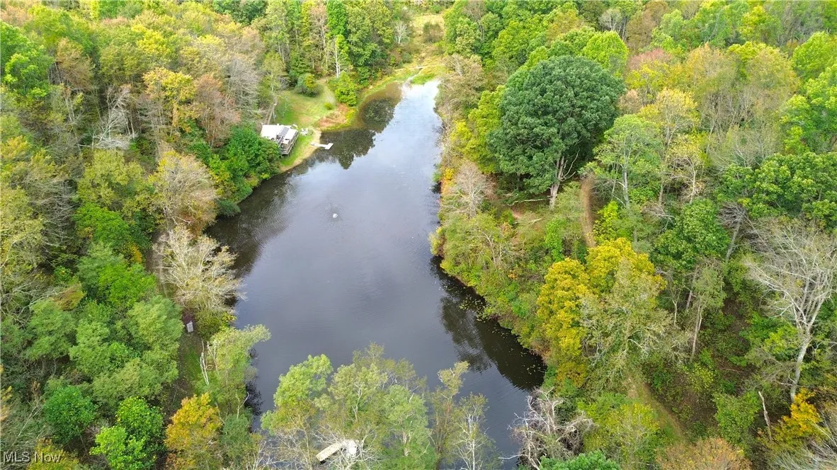 Drone / aerial view of a nearby body of water and a heavily wooded area