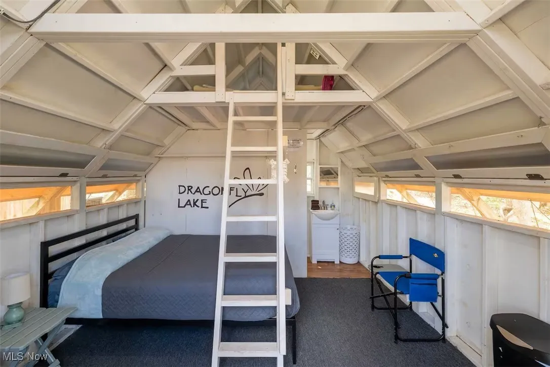 Carpeted bedroom with vaulted ceiling and multiple windows