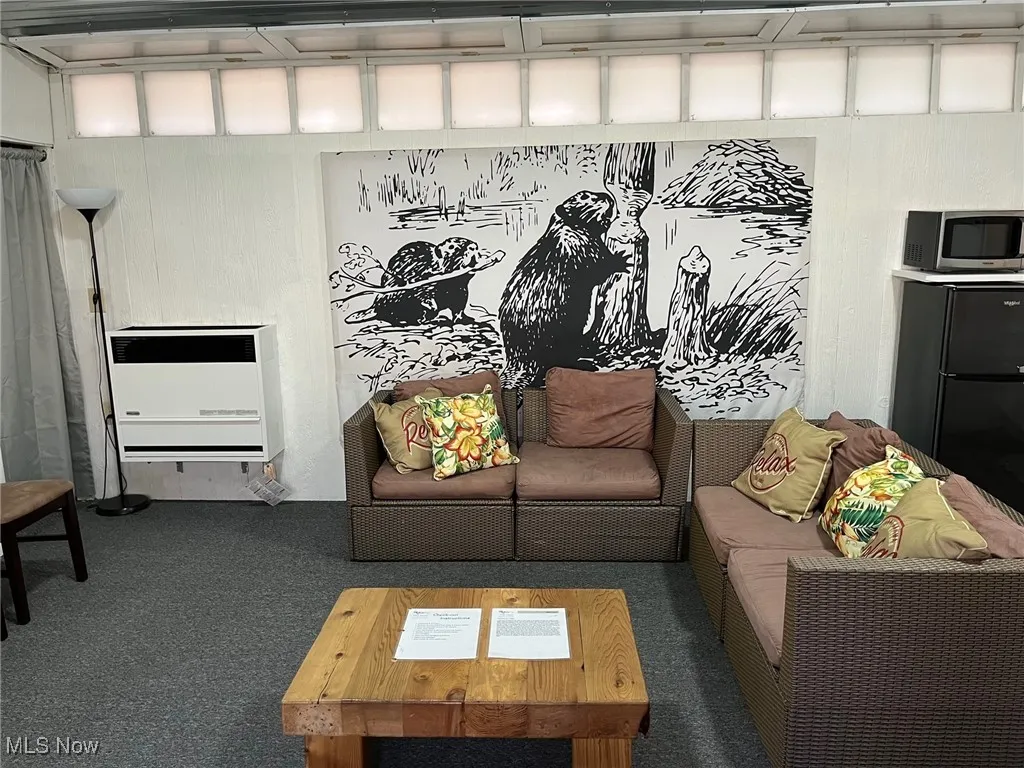 Carpeted living room featuring heating unit and wood walls