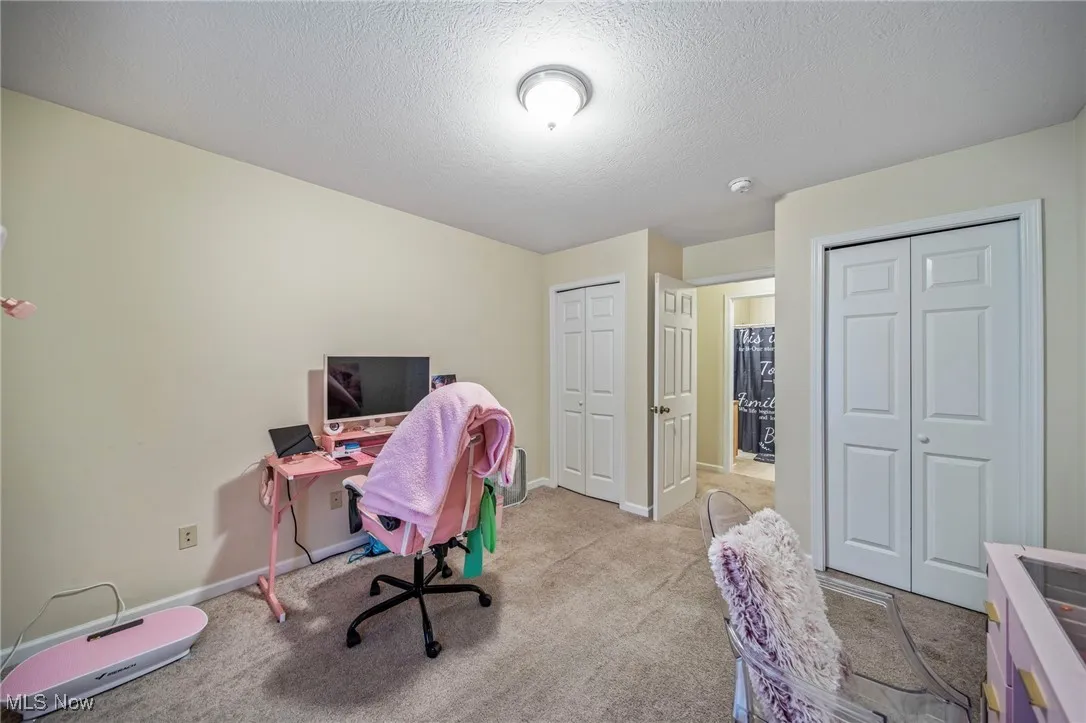Carpeted office space featuring a textured ceiling and baseboards