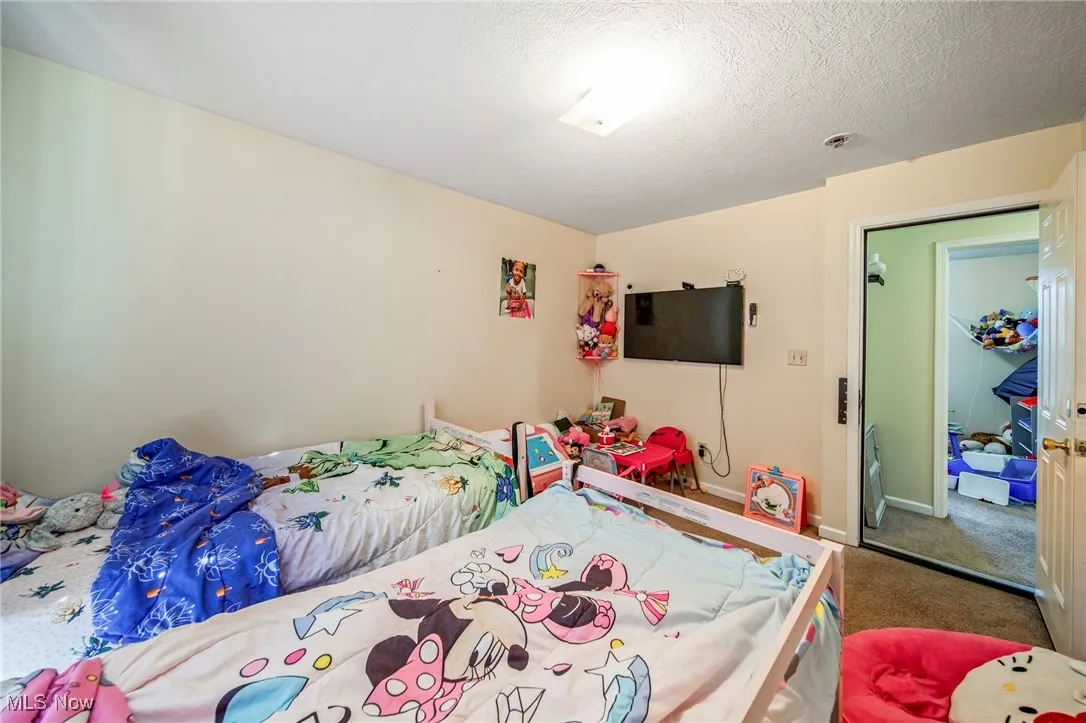 Carpeted bedroom with a textured ceiling and baseboards