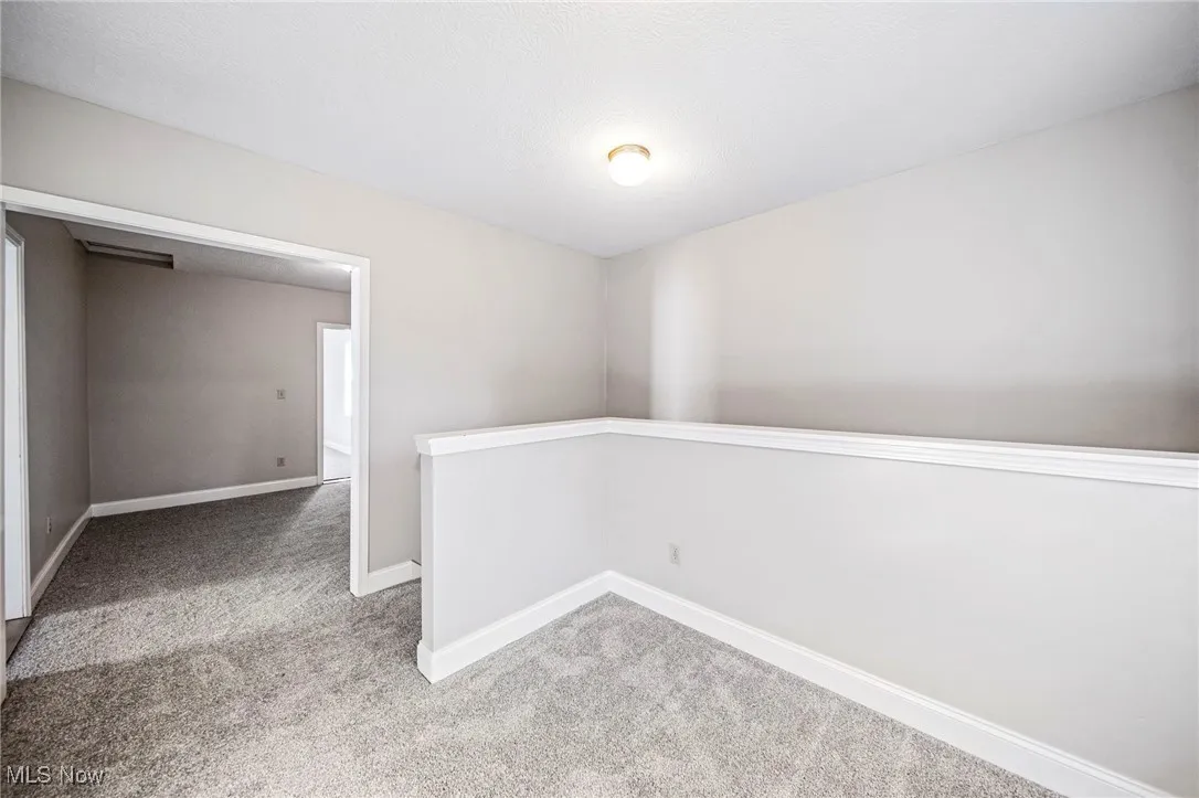 Unfurnished room featuring light colored carpet and a textured ceiling