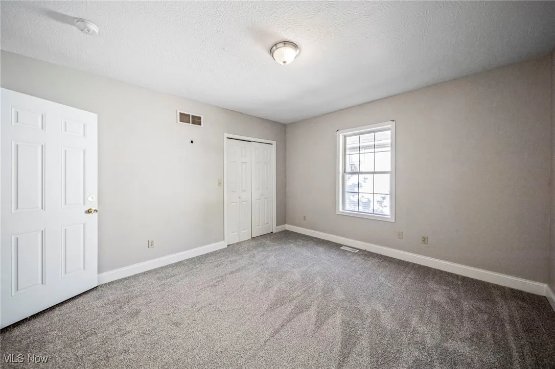Unfurnished bedroom featuring a textured ceiling, carpet, and a closet