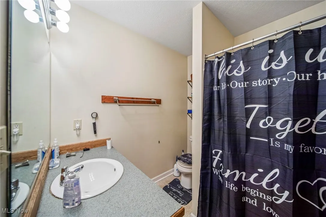 Full bathroom featuring vanity, curtained shower, and a textured ceiling