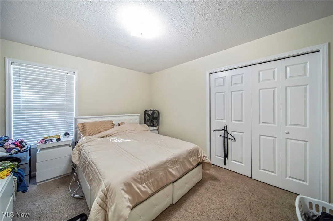 Carpeted bedroom featuring a textured ceiling and a closet