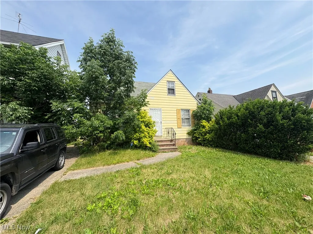 View of property hidden behind natural elements featuring a front yard