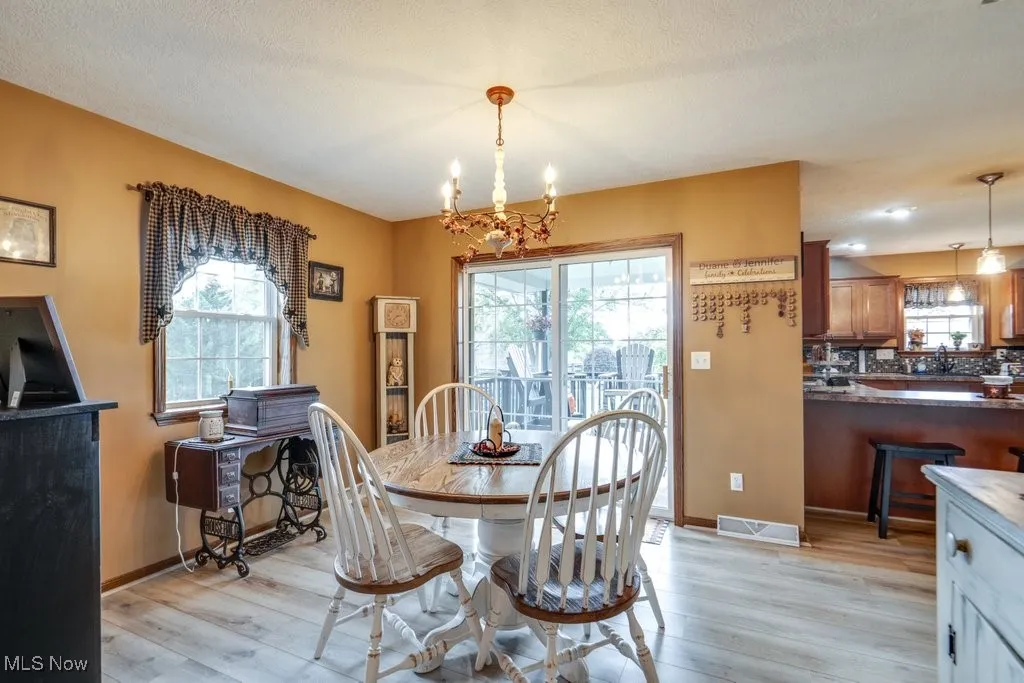 Dining area with light wood-type flooring, a chandelier, and plenty of natural light