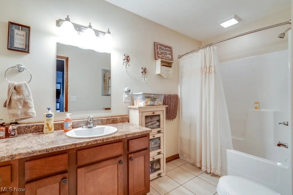 Full bath featuring light tile patterned floors, shower / bathtub combination with curtain, and vanity