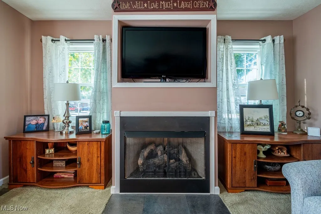 Carpeted living area featuring a fireplace and baseboards