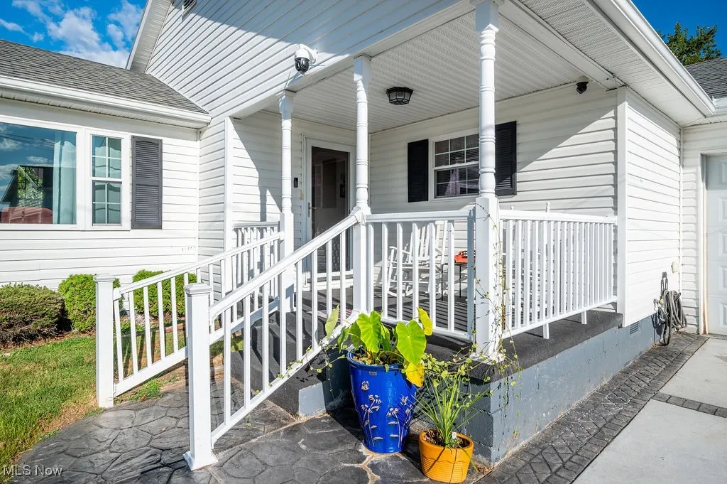 Doorway to property with a shingled roof, a porch, and a garage