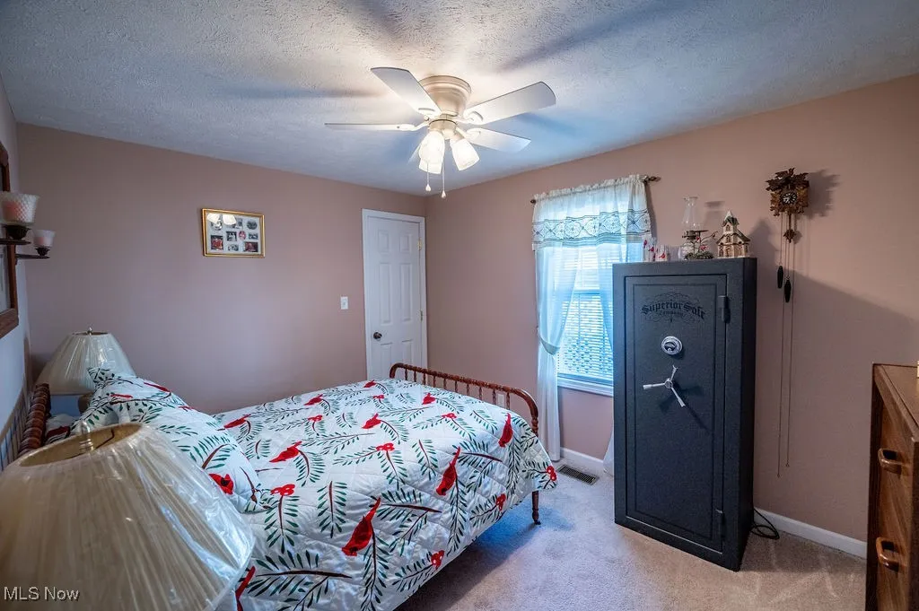 Carpeted bedroom featuring a ceiling fan and a textured ceiling