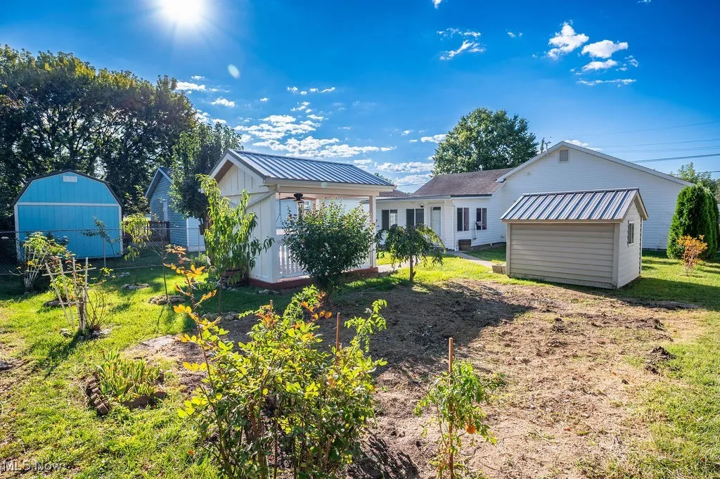 Back of property featuring a lawn, a metal roof, and a storage shed