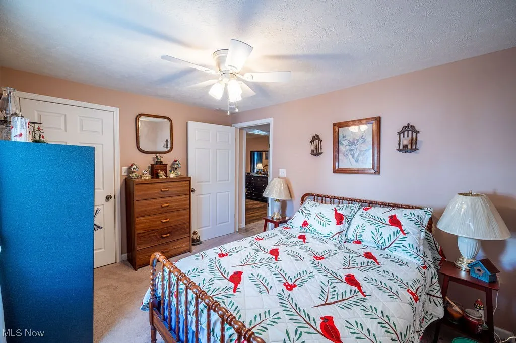 Bedroom featuring light carpet, a closet, a ceiling fan, and a textured ceiling