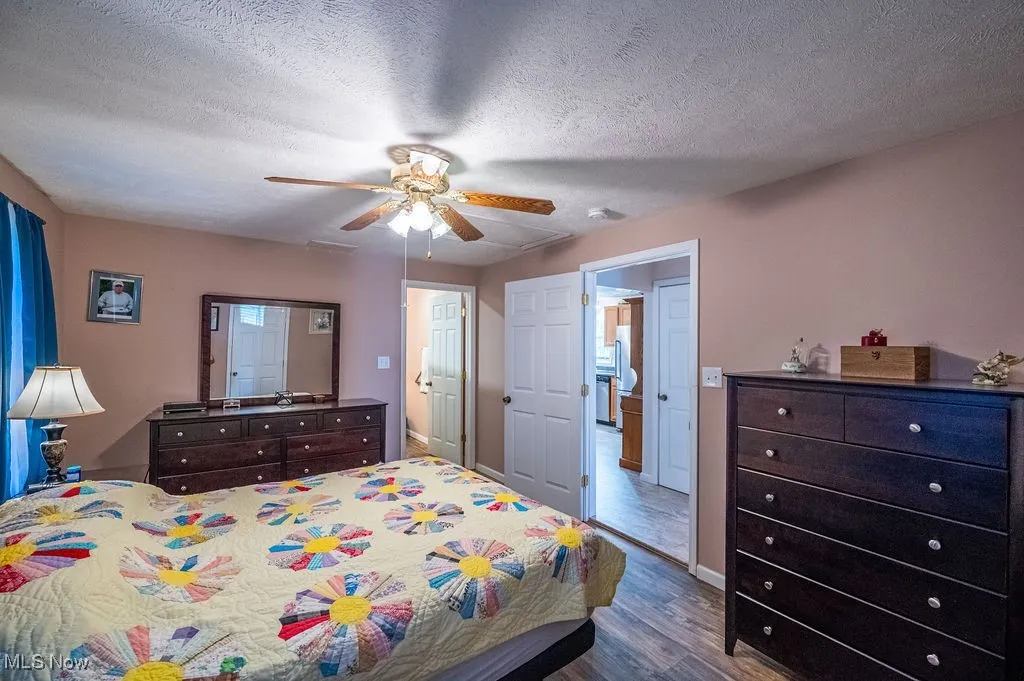 Bedroom featuring dark wood-style flooring, a textured ceiling, and a ceiling fan