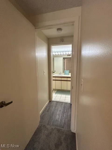 Hallway with dark wood-type flooring and baseboards