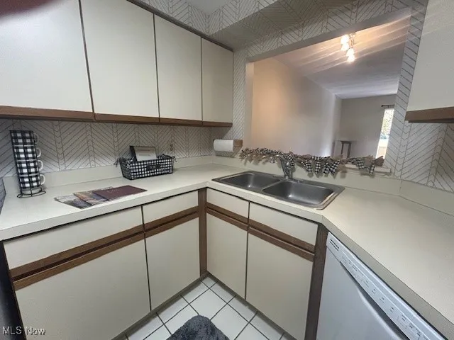 Kitchen with light countertops, white cabinetry, dishwasher, and light tile patterned flooring