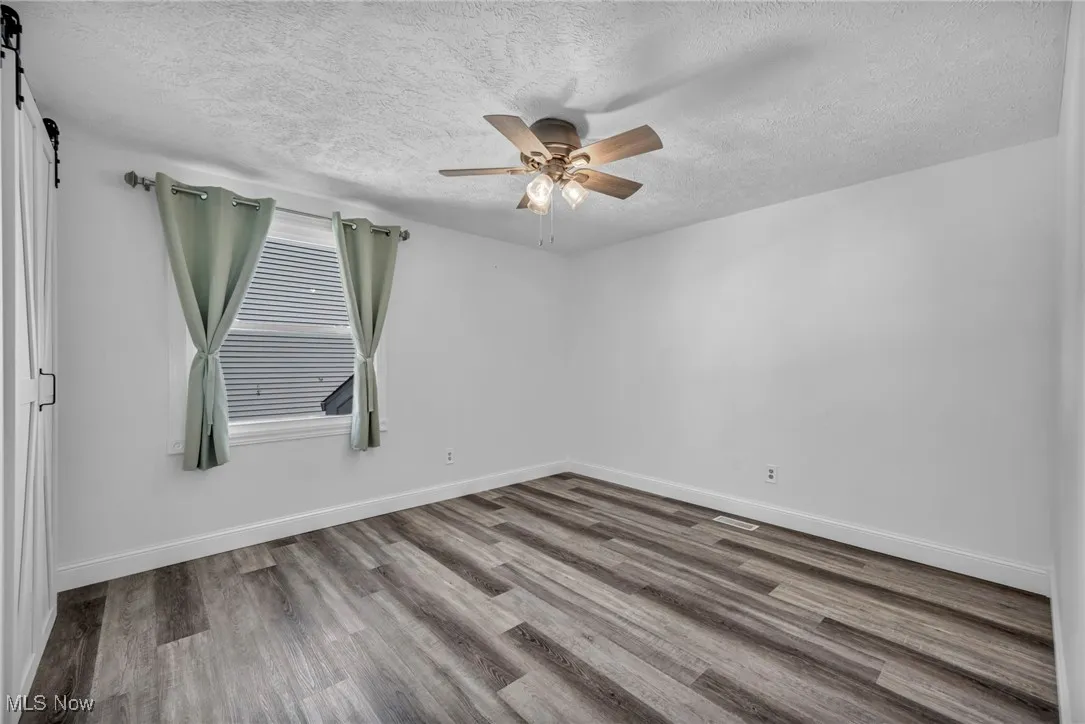 Unfurnished room with light wood-type flooring, a textured ceiling, and a ceiling fan