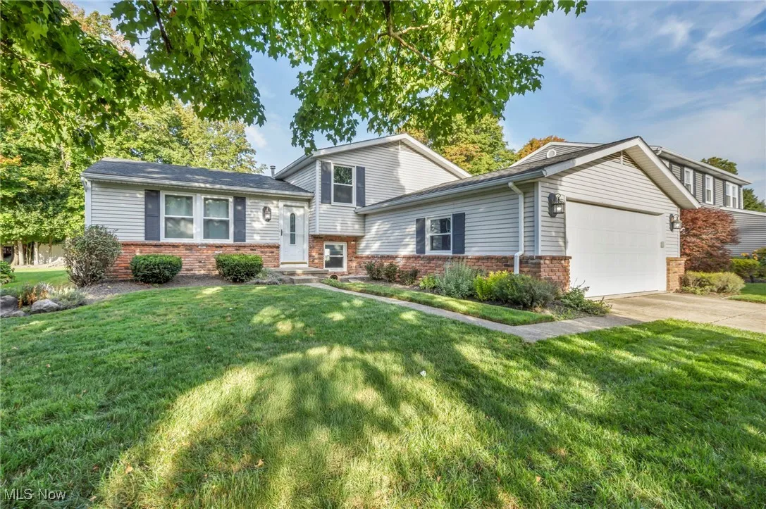 Split level home featuring a front yard, brick siding, and a garage