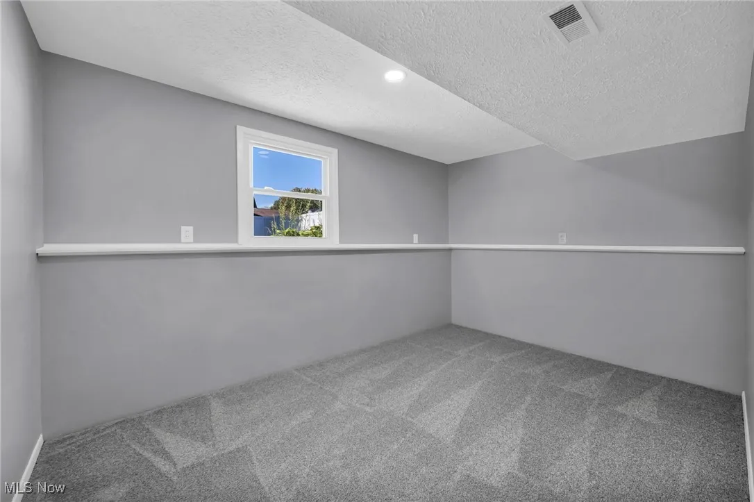 Spare room featuring a textured ceiling, light colored carpet, and recessed lighting