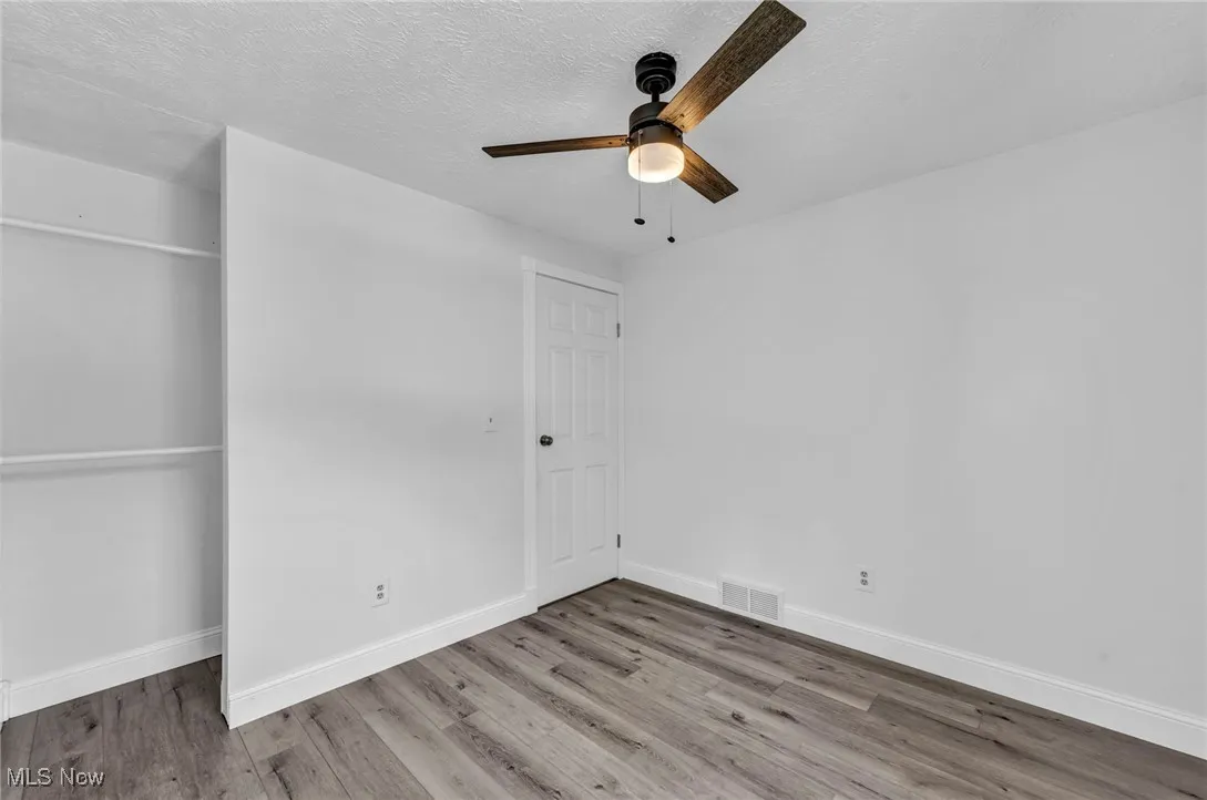 Unfurnished bedroom with wood finished floors, a textured ceiling, ceiling fan, and a closet