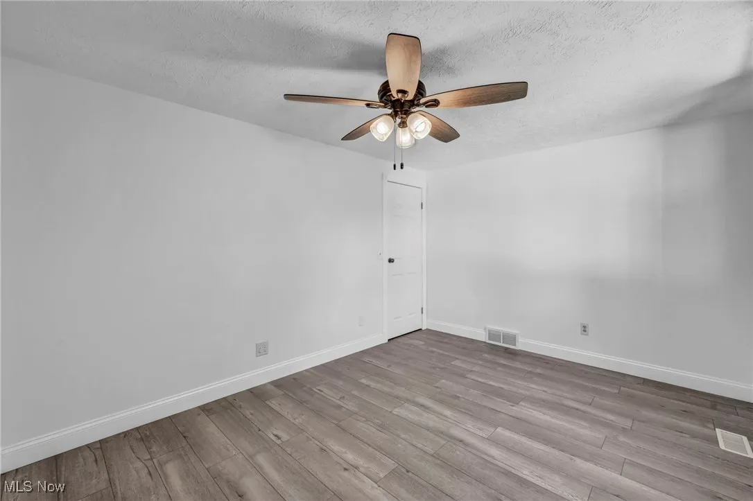 Spare room featuring a textured ceiling, light wood finished floors, and ceiling fan