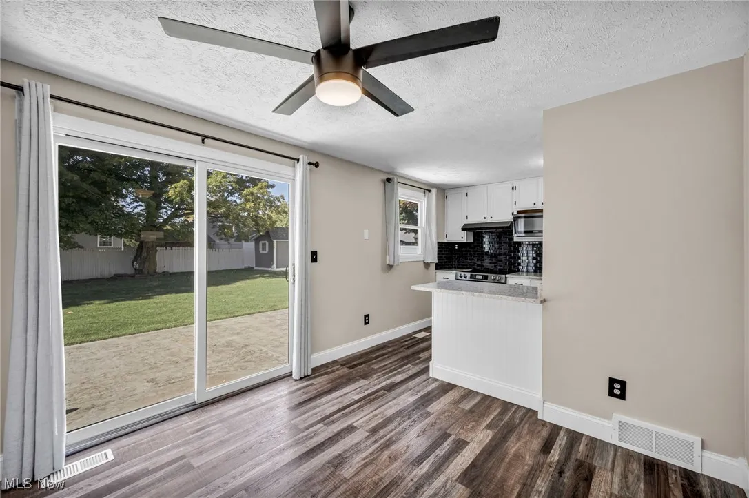 Kitchen featuring plenty of natural light, white cabinetry, dark wood-style flooring, decorative backsplash, and a textured ceiling