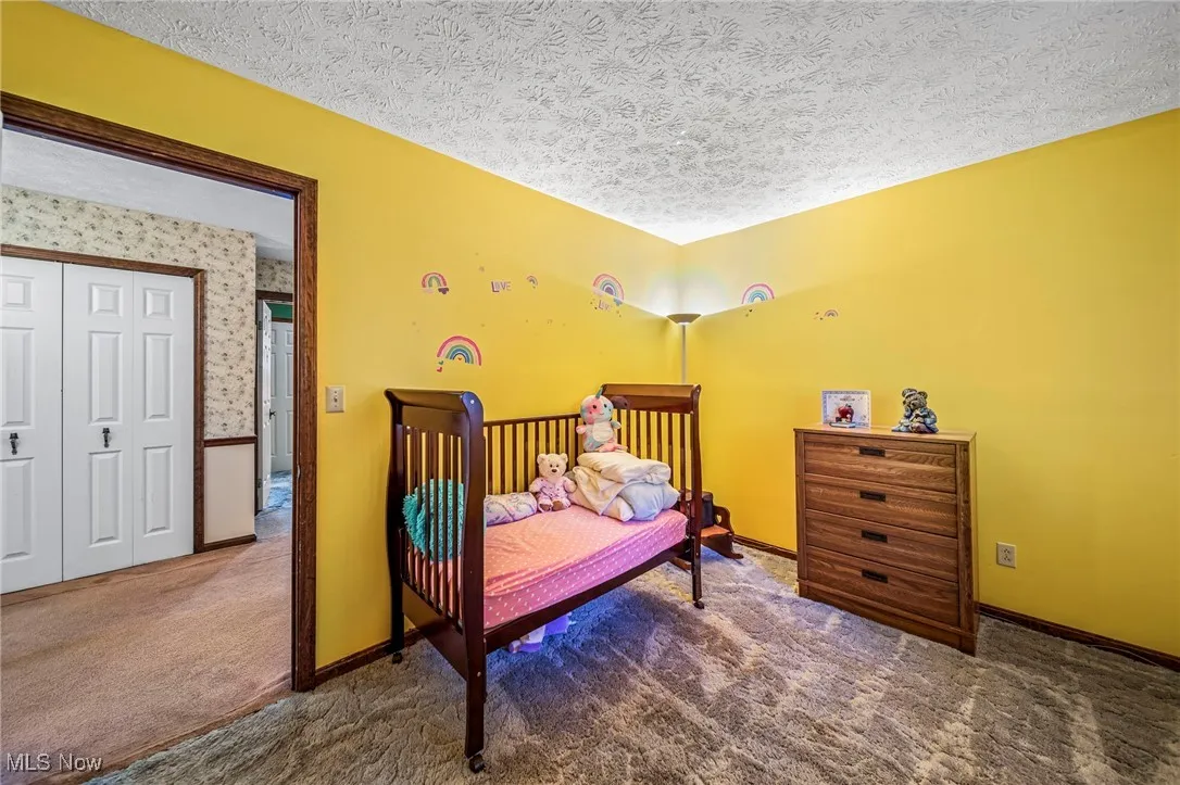 Carpeted bedroom featuring a textured ceiling and baseboards