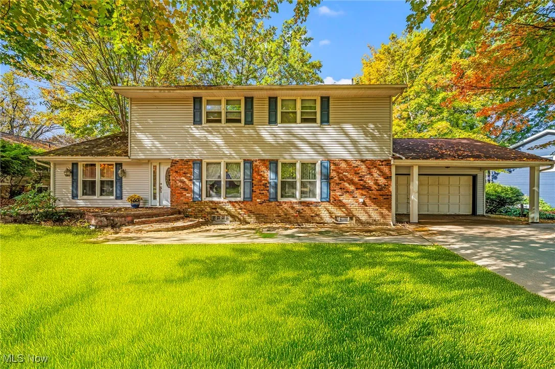 View of front facade featuring a front lawn, brick siding, an attached garage, and driveway