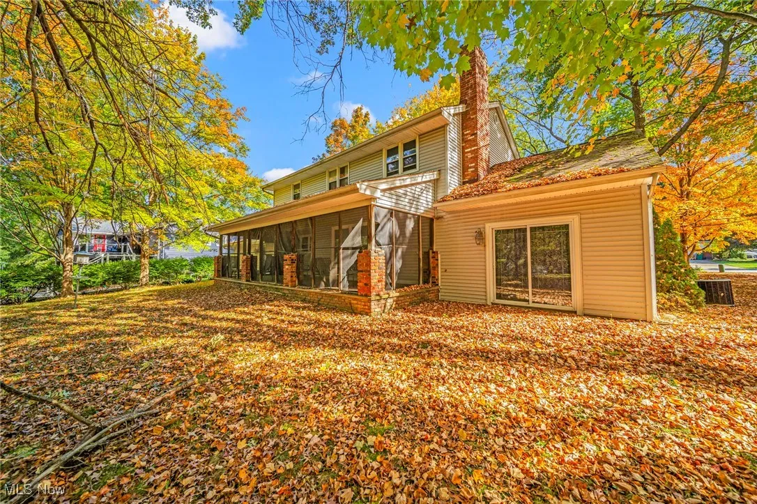 Rear view of house with a sunroom and a chimney