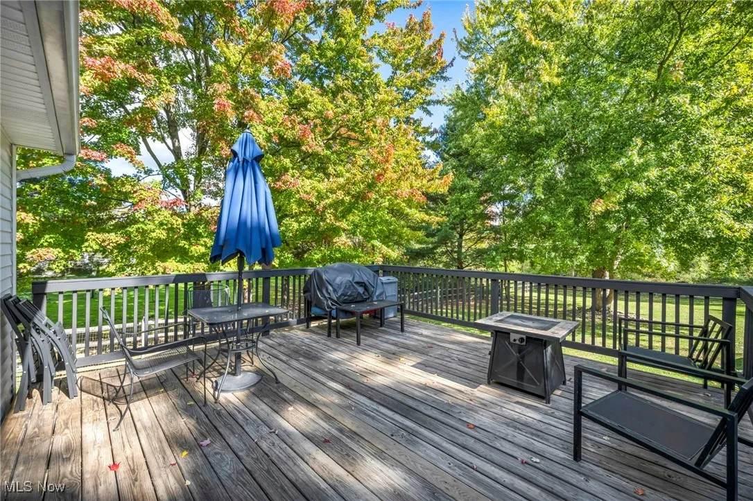 Deck with area for grilling, view of wooded area, an outdoor fire pit, and outdoor dining space