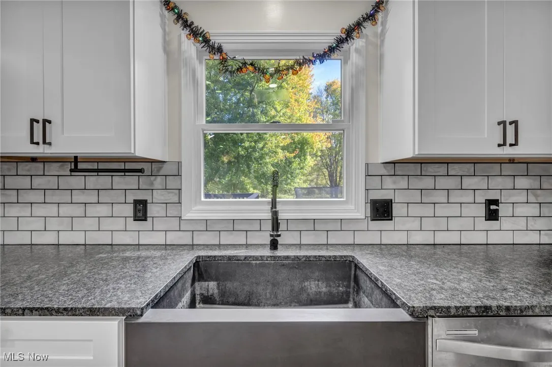 Kitchen featuring white cabinetry, backsplash, and stainless steel dishwasher