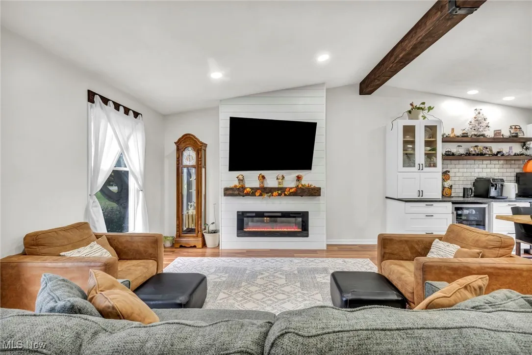 Living area featuring recessed lighting, a dry bar, a fireplace, beverage cooler, and light wood-type flooring