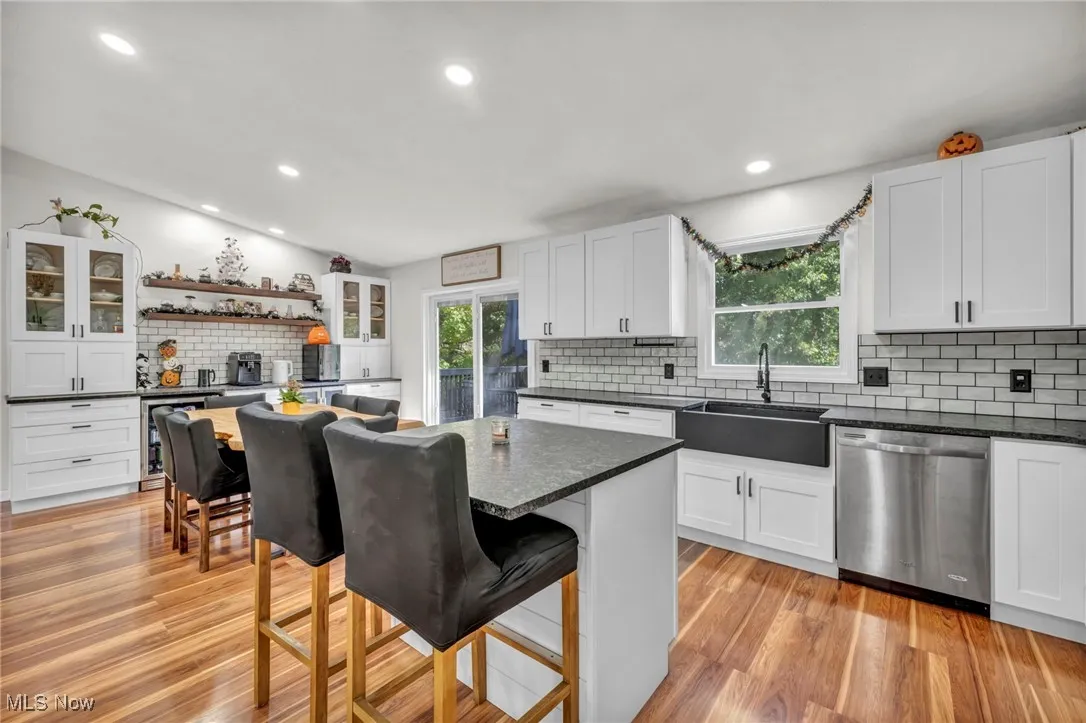 Kitchen with open shelves, tasteful backsplash, glass insert cabinets, a breakfast bar, and white cabinets