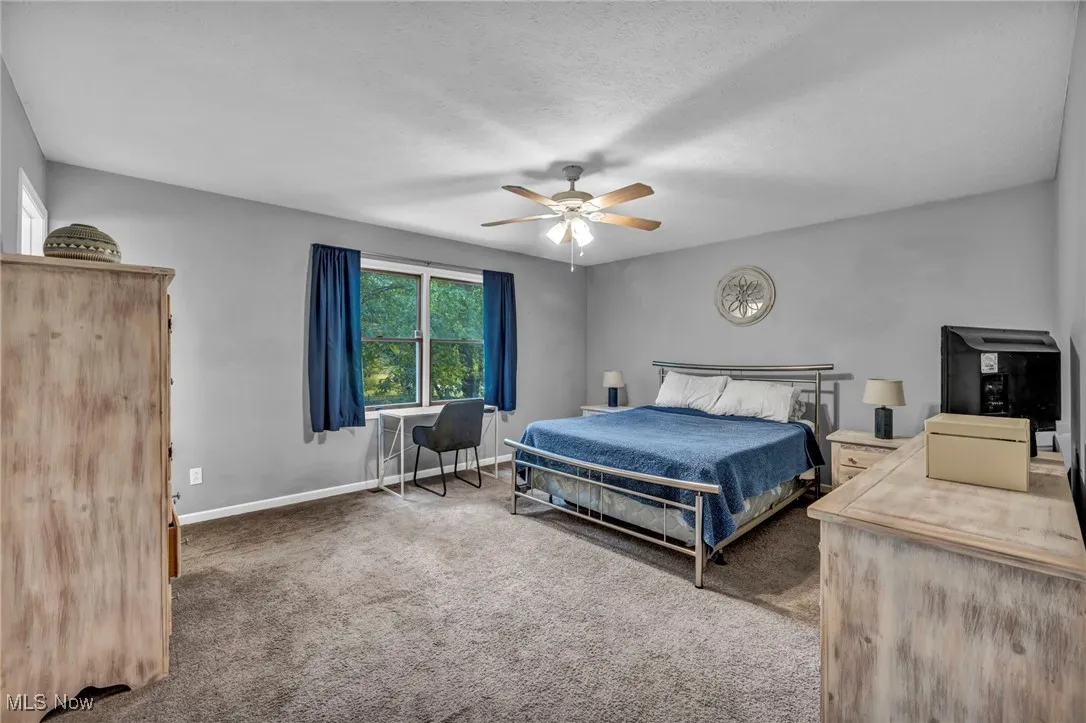 Carpeted bedroom with a ceiling fan and a textured ceiling
