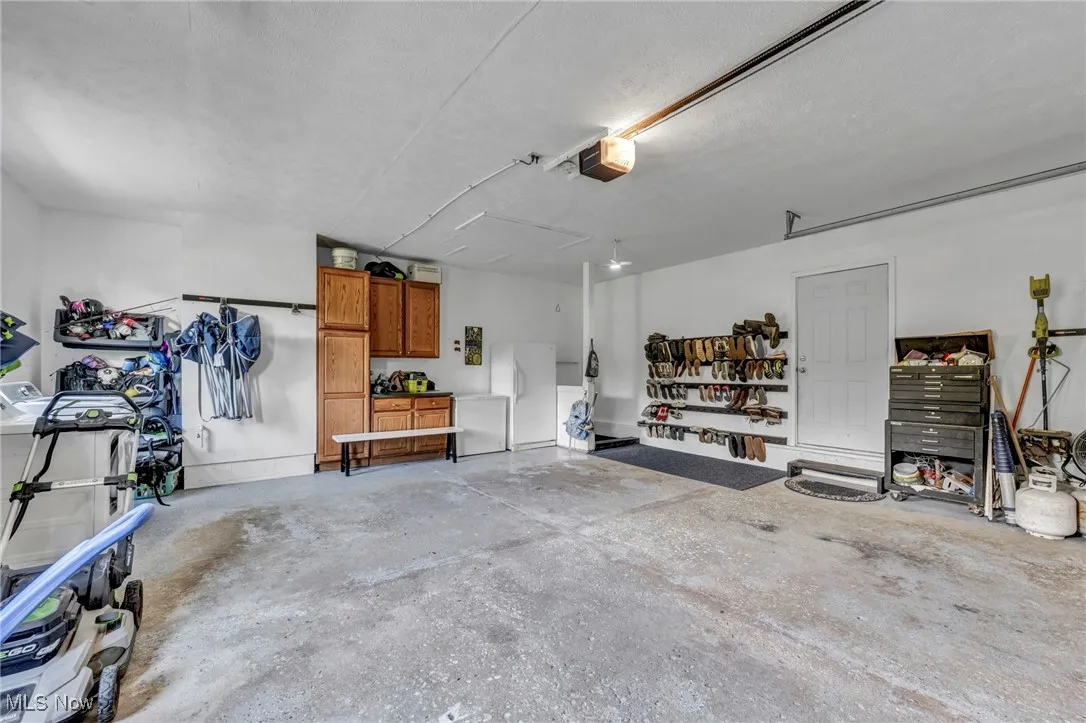 Garage with freestanding refrigerator, a garage door opener, and a workshop area