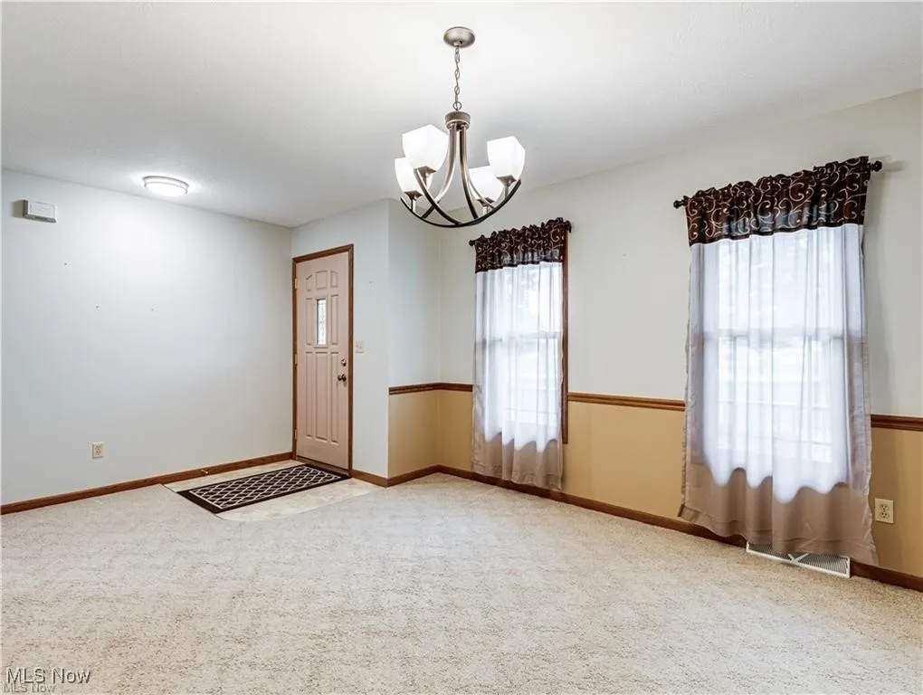 View of dining room with chandelier and showing front door entrance