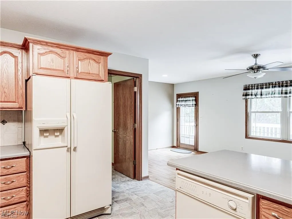 Kitchen featuring white appliances, light countertops, plenty of natural light, and a ceiling fan