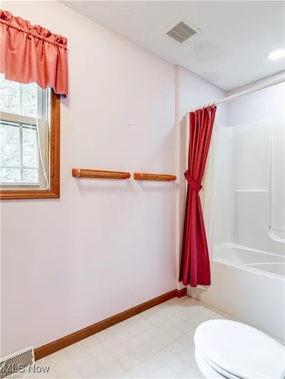 Primary bathroom featuring shower / tub combo and commode