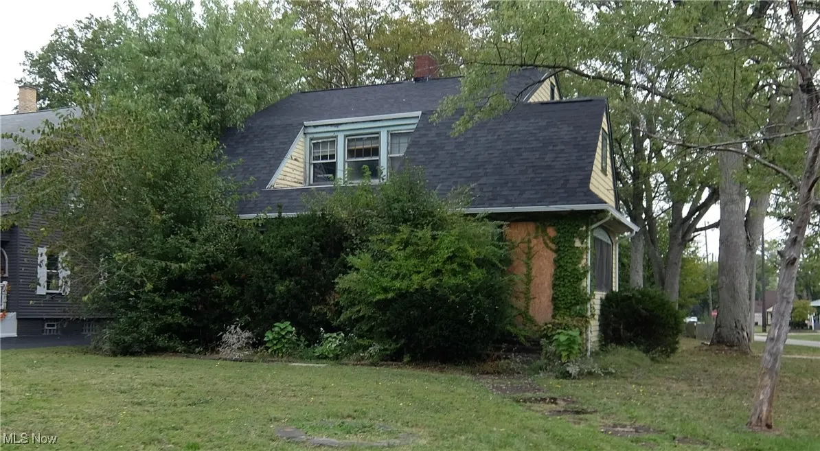 View of front of property featuring a shingled roof, a front lawn, and a chimney
