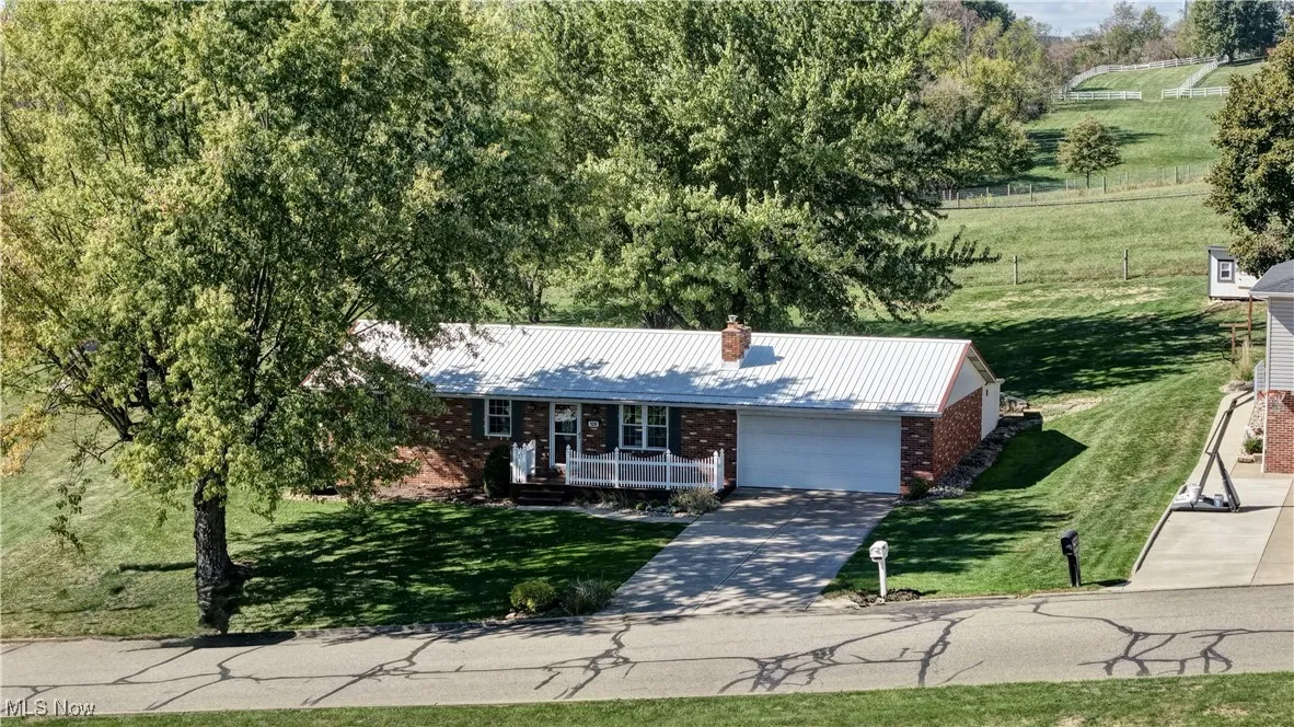 Ranch-style house featuring brick siding, a metal roof, driveway, and a front yard