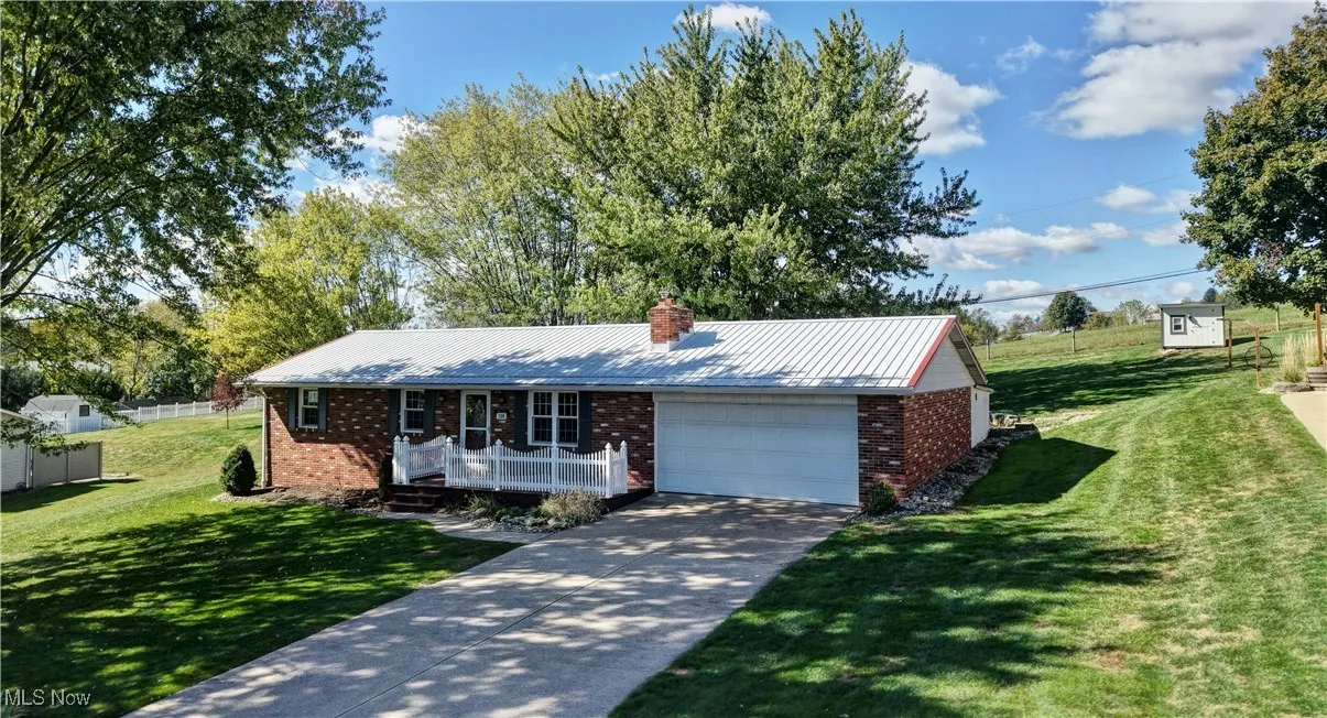 Ranch-style house featuring a metal roof, brick siding, and concrete driveway