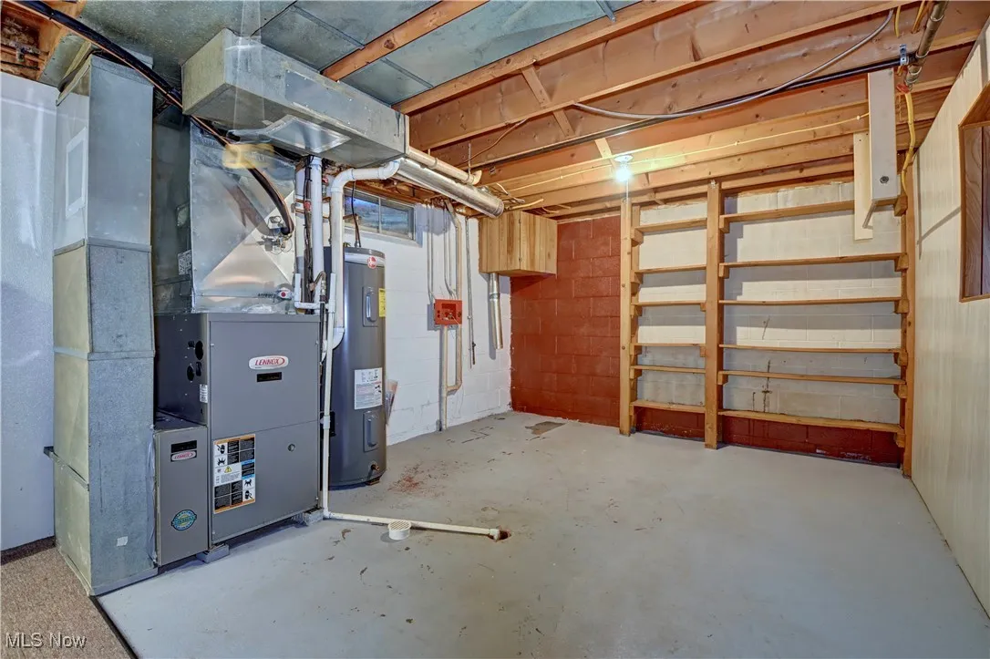 Unfinished below grade area with electric water heater and heating unit